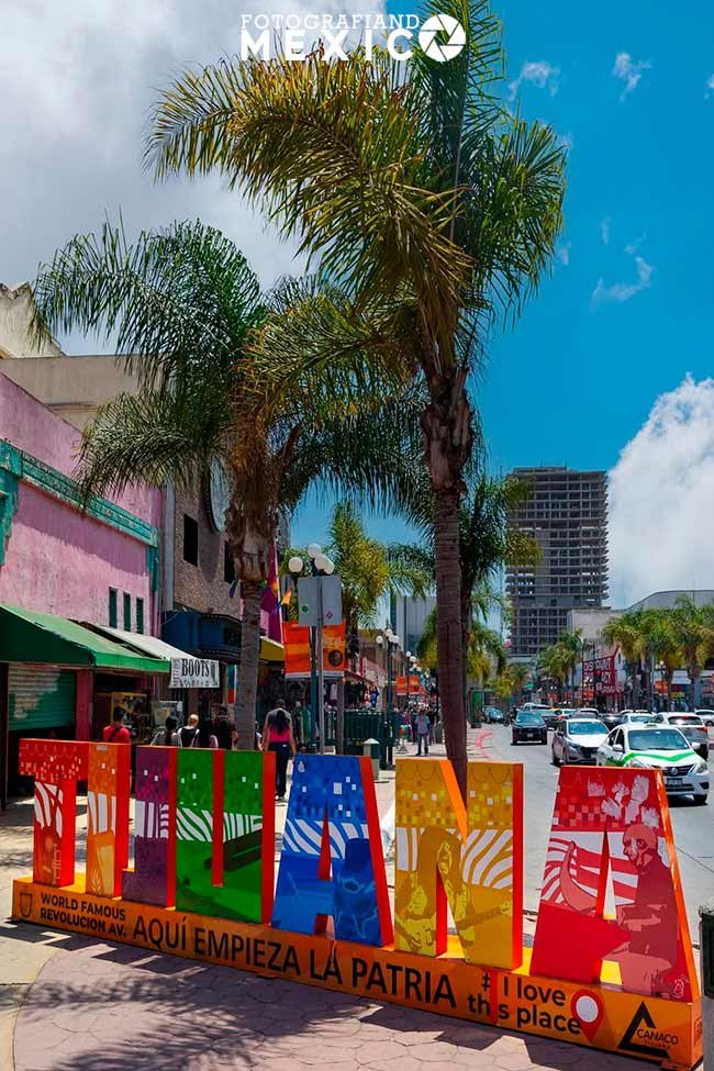 Letrero monumental de colores de Tijuana en la Avenida Revolución con la frase aquí empieza la patria junto a palme