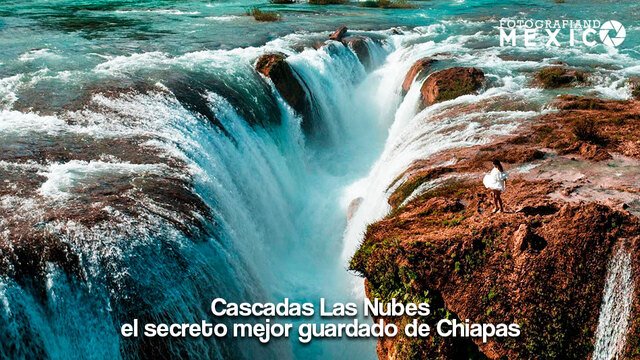 Vista aérea de una gran cascada de agua color turquesa cayendo hacia un abismo con una persona parada al filo de la roca