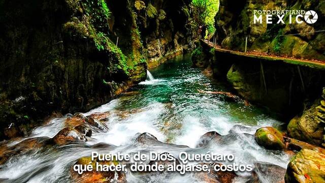 Vista de un rio encajonado entre altas paredes rocosas cubiertas de musgo verde con un andador de madera a un costado