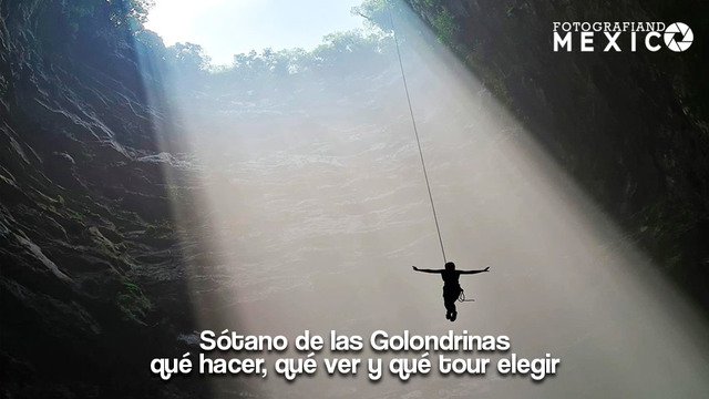 Silueta de un explorador descendiendo en rappel por una cuerda hacia el interior del Sotano de las Golondrinas con rayos de sol