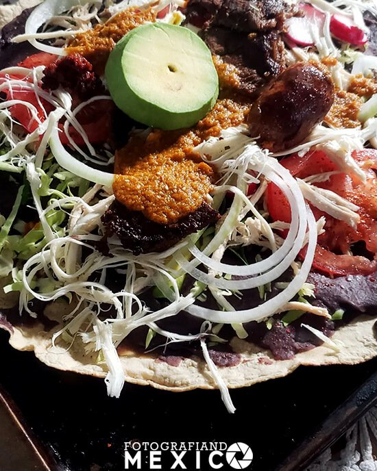 La tlayuda es un platillo típico de Oaxaca que se hace con una tortilla de maíz, asiento, frijoles, queso y carne.