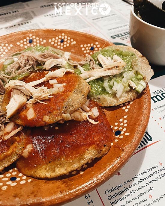 Plato de chalupas poblanas bañadas con salsa verde o roja y cubiertas con carne, cebolla y queso
